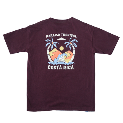 T-shirt color vino con ilustración de paisaje tropical en tonos suaves, colgada en entorno natural.