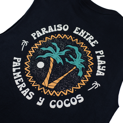 Camisa sin mangas con ilustración de playa con palmeras y cocos, colgada frente a vegetación tropical.